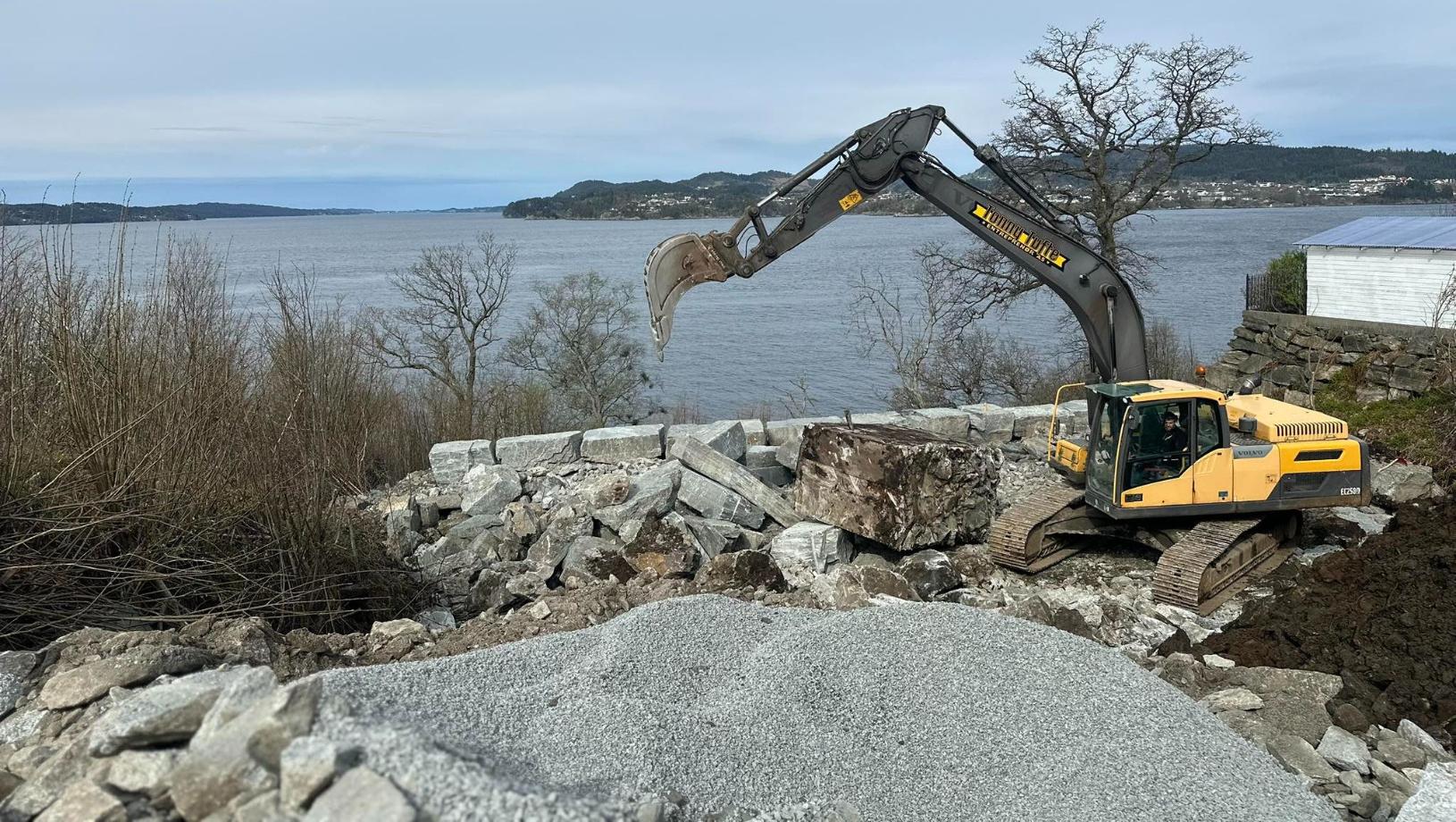 Gravemaskin som jobber ved vannkanten